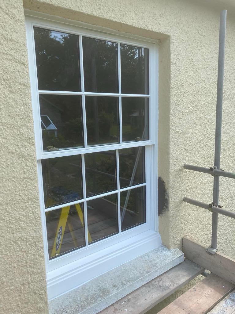 Professional window installation in progress on a residential property in Plymstock Devon, showing a fitter securing a new double-glazed window into place with clean, modern white uPVC framing