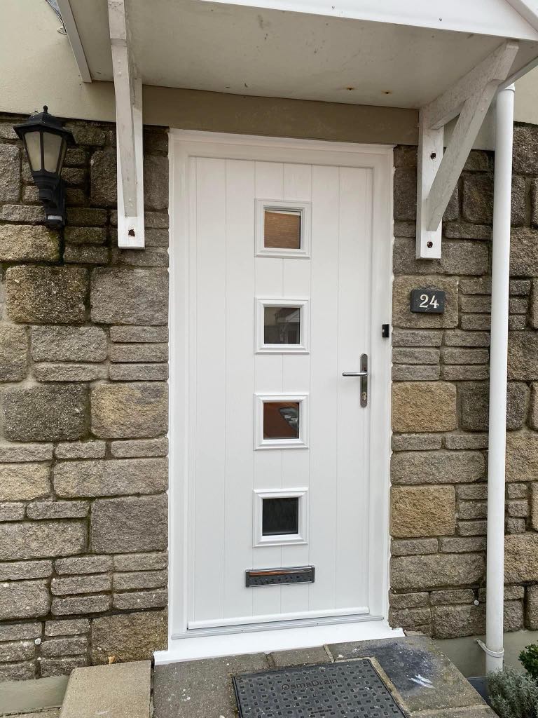 Installer fitting a new composite front door on a residential home, with modern design and secure locking system, replacing an old, worn-out door in Plymouth