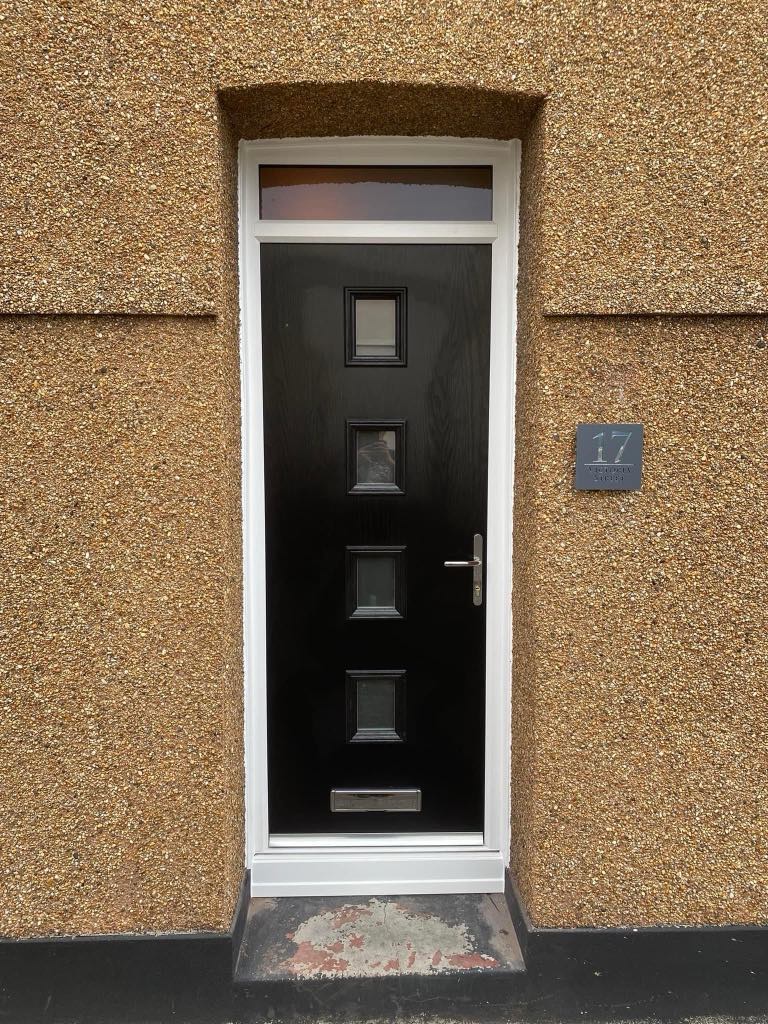 Newly installed sleek black front door on a residential home in Torpoint, featuring a modern design with chrome handle and letterbox.