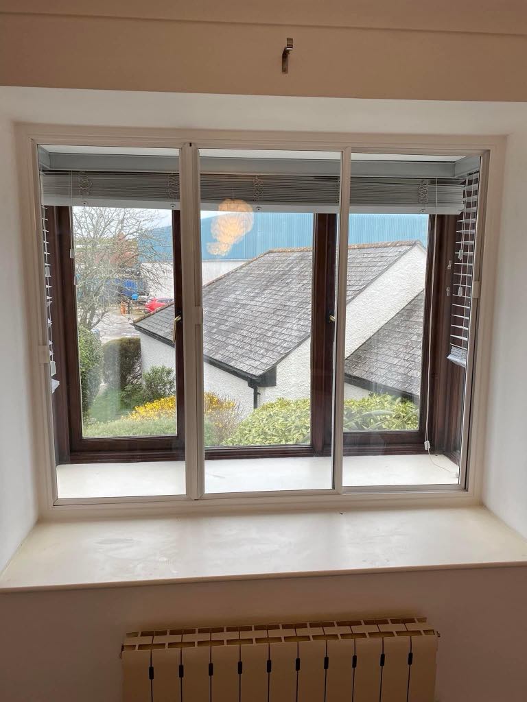Professional window installation in progress on a residential property Cornwall, showing a fitter securing a new secondary-glazed window into place with clean, modern white uPVC framing.