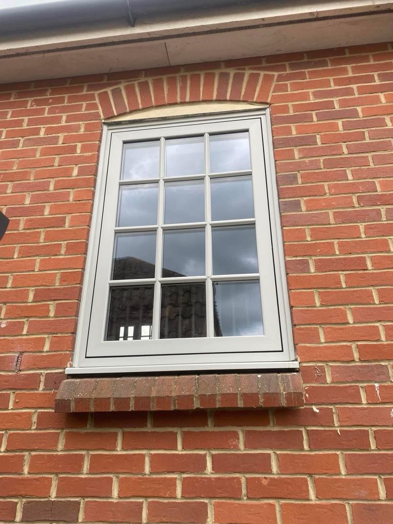 Professional window installation in progress on a residential property Taunton, showing a fitter securing a new double-glazed window into place with clean, modern white uPVC framing.