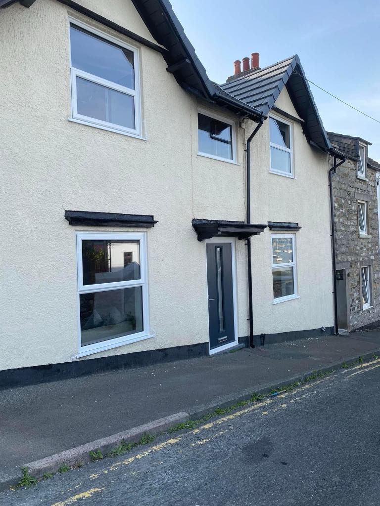 Professional window installation in progress on a residential property in Torpoint Cornwall, showing a fitter securing a new double-glazed window into place with clean, modern white uPVC framing.