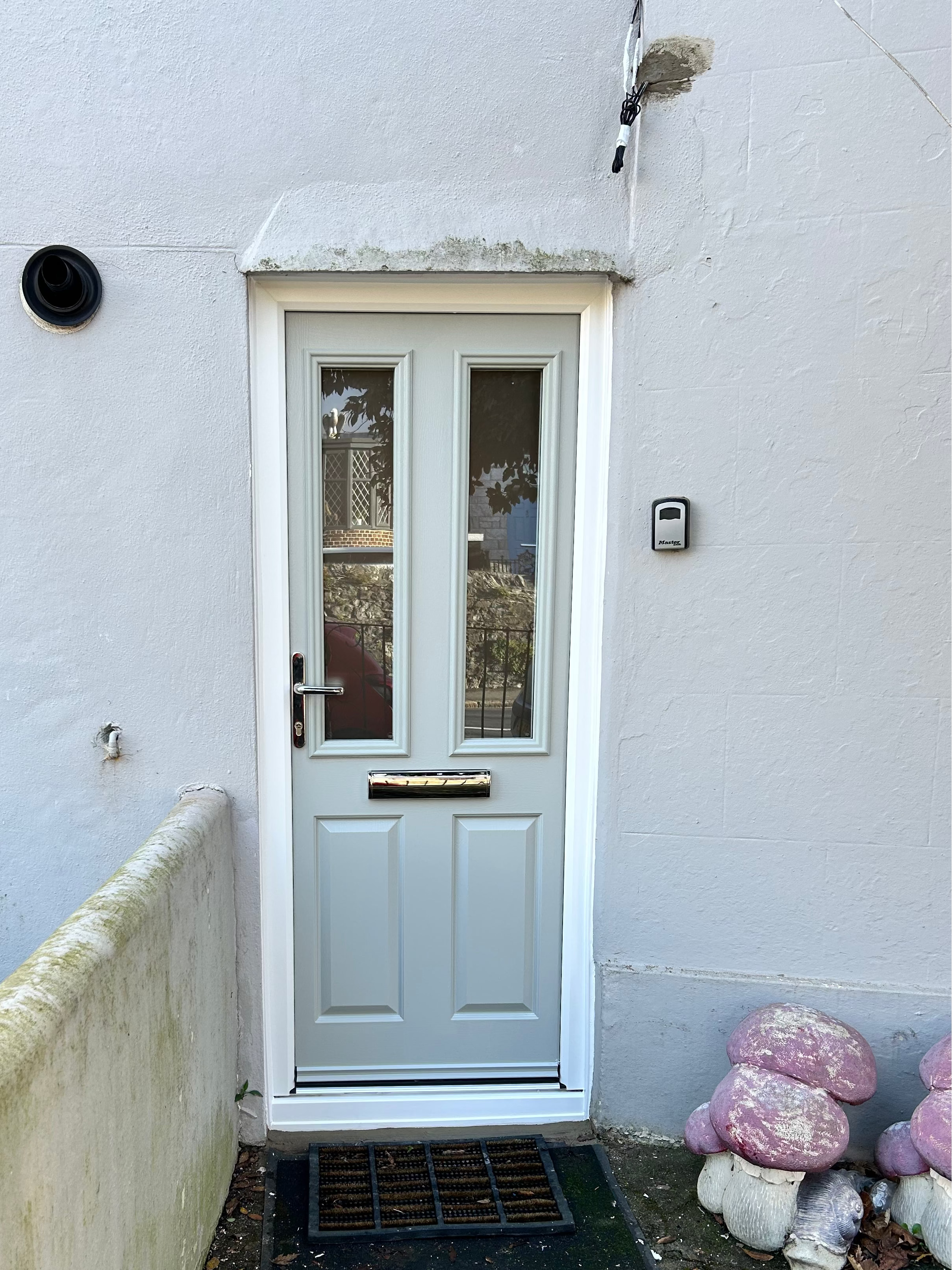 Agate grey composite front door with glass panels on a light gray wall.